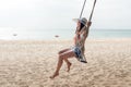Summer Vacations. Lifestyle women relaxing and enjoying swing on the sand beach, fashion stunning women with white dress on the tr Royalty Free Stock Photo
