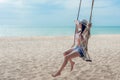 Summer Vacations. Lifestyle women relaxing and enjoying swing on the sand beach, fashion stunning women on the tropical island so Royalty Free Stock Photo