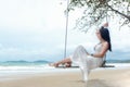 Summer Vacations. Lifestyle women relaxing and enjoying swing on the sand beach, fashion stunning women on the tropical island so Royalty Free Stock Photo