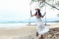 Summer Vacations. Lifestyle women relaxing and enjoying swing on the sand beach, fashion stunning women with white dress on the tr Royalty Free Stock Photo