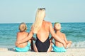 Mother and two sons are sitting on the sand and looking at the sea. Summer vacations. Royalty Free Stock Photo