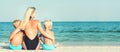 Mother and two sons are sitting on the sand and looking at the sea. Summer vacations. Royalty Free Stock Photo