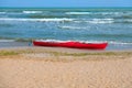 Summer Vacations. The red kayak is parked on the sandy beach on a sunny day, waiting for people to paddle out to sea. Royalty Free Stock Photo