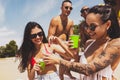 Group of young people, men and women resting on the beach, drinking cool drinks, having fun, sunbathing Royalty Free Stock Photo
