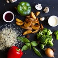 Summer vegetables on black wood background. Red and green pepper broccoli rice and fried potatoes Royalty Free Stock Photo