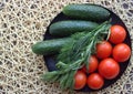 Summer vegetarian flatlay: beautiful red tomatoes, cucumbers, dill and tarragon on a wicker napkin