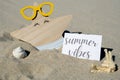 SUMMER VIBES text on paper greeting card on background of funny starfish in glasses summer vacation decor. Sandy beach Royalty Free Stock Photo