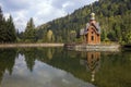 Summer view of beautiful wooden orthodox chapel in ecological area on small artificial island on background of green spruce mounta Royalty Free Stock Photo