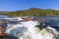 A summer view of the Namsen River in Namsskogan, Trondelag, Norway, with cascading waters over large boulders,