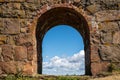 Summer view through an old medieval stone wall arched gate at Varberg Fortress in Sweden with blue cloudy sky in the background. Royalty Free Stock Photo