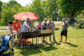 Summer view of two males barbecue grilling outdoors on a green lawn in a park with people and parasols on the Swedish national day