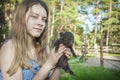 In the summer in the village a girl holds a small pig in her hands