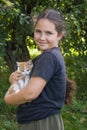 In the summer in the village, a girl holds a white-red little kitten in her arms Royalty Free Stock Photo