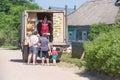 In summer, in the village on the street, young people are looking at a pink motorcycle Ural, which stands on the side of the road.