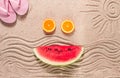 Summer wallpaper, drawing on sand, sea waves and sun, face shape of summer fruits, pink flip-flops, top view, no people Royalty Free Stock Photo