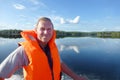 Summer water landscape. Blue sky and clear water of Lake Pyaozero with reflected clouds. A man in life jacket manages motor boat. Royalty Free Stock Photo