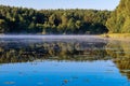 Summer water scenery. Fishing on a forest lake in the early morning. Fog over the water, forest, water surface