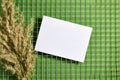 Summer wedding stationery mock-up scene. Blank greeting card above fence background with reed plant. Feminine flat lay