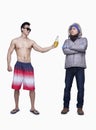 Summer and winter, young man offering beer to man in winter coat, opposite, studio shot