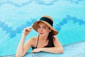 Young woman sitting near the pool. Sexy girl with healthy tanned skin. Female with sun hat relaxing in swimming pool Royalty Free Stock Photo