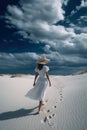 Summer woman in hat walking away in white sand , blue sky. Ai generative