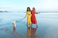 Summer. Women With Dog On Beach. Fashion Girls In Maxi Bohemian Clothing Walking With Pet On Dog-Friendly Coast