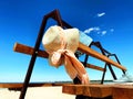 Summer women hat with  white bow  and  blue  jeans with sneakers ,clothes beachwear on wooden  bench white beach sand blue sky rel Royalty Free Stock Photo