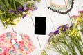 summer women set with smart phone, dress, colorful flowers, cosmetics makeup, bijou and essentials on white wooden background Royalty Free Stock Photo