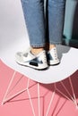 Summer women& x27;s shoes on a colored background. The model is standing on a chair. Light shoes with spikes. rear view.