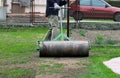 Summer worker pulls lawn roller for flatten garden. Heavy, iron cylinder tramples soil and then man can plant seeds. Important