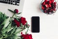 summer working place. freelance concept. stylish laptop with phone, strawberries and cherries and beautiful red peonies on white Royalty Free Stock Photo