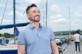 Summer Young cheerful bearded man relaxing on sailboat posing and looking at far on background of boats sky and folded wings Royalty Free Stock Photo