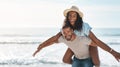 Summers our season. Portrait of a young man piggybacking his girlfriend at the beach. Royalty Free Stock Photo