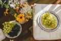 Summertime in countryside. Wildflowers bouquet on background of fresh blueberries, blackberries and grapes in sunlight in rustic Royalty Free Stock Photo