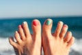 Summertime enjoyment! Feet on the beach. Blue ocean waves backgr