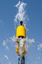 Summertime fun for the kids at the splash pad to play yellow fountain spraying water to bright blue sky portrait view Royalty Free Stock Photo