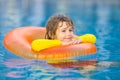 Summertime fun. Little kid swimming in pool. Kid in swimming pool relax and swim on inflatable ring. Summer vacation