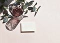 Summertime minimal mockup still life scene with blank invitation card, color glass and eucalyptus branch on beige background.