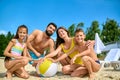 Summertime by river, family mother father son and daughter playing with inflatable ball on sandy beach. Royalty Free Stock Photo