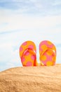 Summertime Season, colorful spotty sandals or flip-flop on the sandy beach with sunny colorful blue sky background and copy space. Royalty Free Stock Photo
