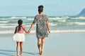 Summertime strolls on the beach. Rear view shot of a mother and her little daughter enjoying a walk along the beach. Royalty Free Stock Photo