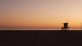 Summertime travel concept. Dark silhouette, iconic retro wooden lifeguard watch tower against sunset orange sky. Contrast