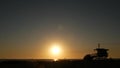 Summertime travel concept. Dark silhouette, iconic retro wooden lifeguard watch tower against sunset orange sky. Contrast