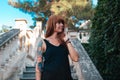 Summertime and travel. Portrait of young tanned woman with tattoo sleeve is walking down the stone steps. Bottom view Royalty Free Stock Photo