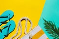 Summertime and vacation concept. Flip flops, beach bag and palm leaf on bright yellow and aquamarine background with Royalty Free Stock Photo