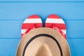 Summertime vacation concept. Top above overhead view close-up photo of a pair of flipflops and a hat isolated on blue wooden