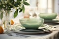 Summery dinner table with green aesthetics. White plates and light green bowls, wine glass, green leaves, lilacs. White