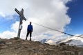 Summit cross and male mountaineer on mountain Weissspitze with panorama in Hohe Tauern Alps