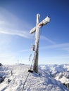 Summit cross with prayer flags on a high peak in winter with frozen ice crystals on the beam