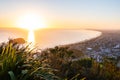 From the summit of Mount Maunganui at daybreak golden glow of rising sun, distant horizon and long leading coastline of Bay of